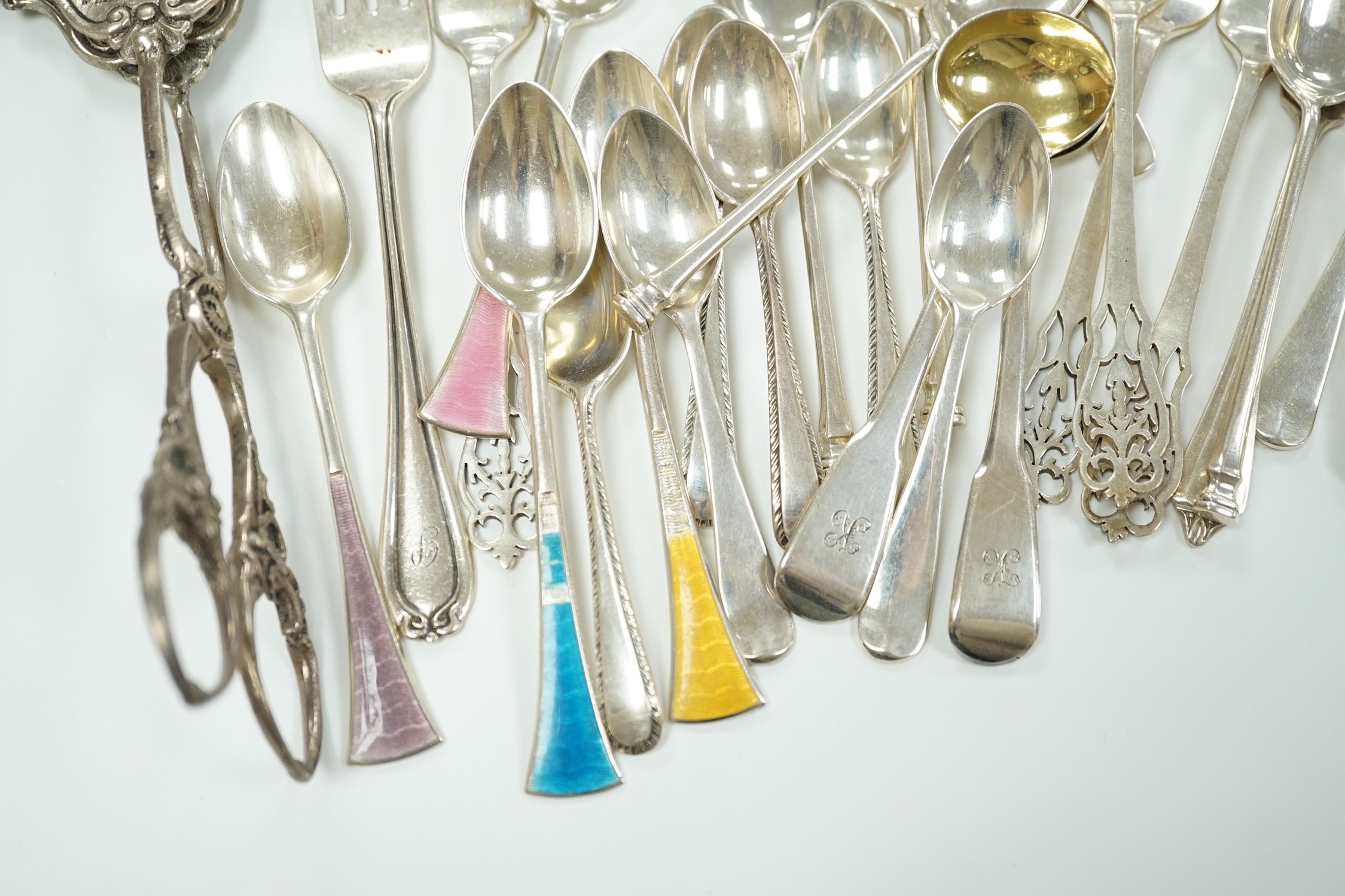 A small collection of assorted silver flatware including teaspoons, enamelled spoons(a.f.), butter knives, pastry forks and a pair of continental 830 white metal cake tongs, gross weight 14.4 oz.